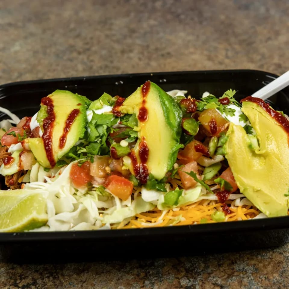 Burrito Bandito's burrito bowl with avocado, salsa, sour cream, and lime in a black container.