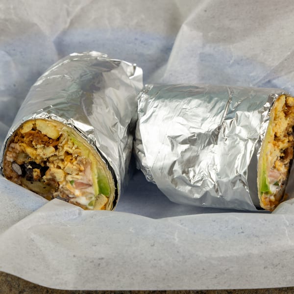 Two foil-wrapped Burrito Bandito burritos, one cut open to reveal chicken, beans, and avocado.